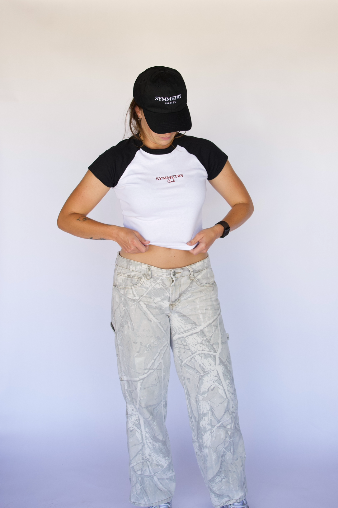 Person wearing a black and white t-shirt with text and light-colored pants against a white background