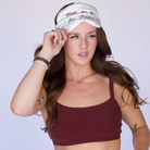 Woman wearing a maroon sports bra and shorts with a white eye mask on against a light background