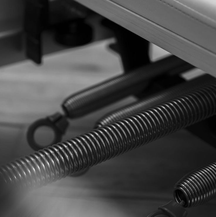 Close-up of metal reformer springs and a coil spring on a blurred background